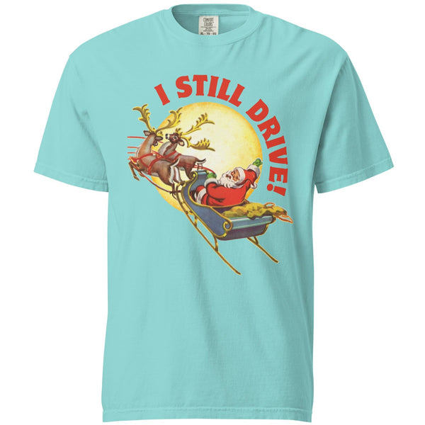 Product mockup  of a lagoon blue tshirt with a vintage Santa Claus driving his sleigh and two deer across a moon. Above the moon text says, I still drive!