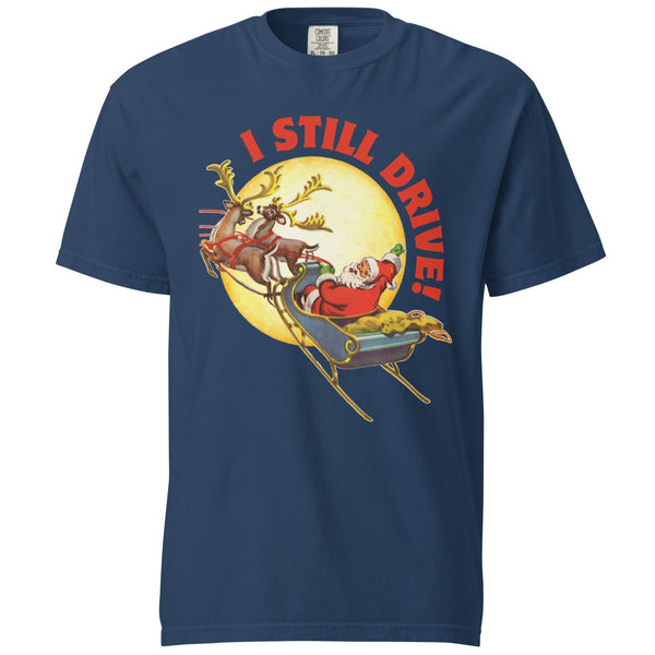 Product mockup  of a blue tshirt with a vintage Santa Claus driving his sleigh and two deer across a moon. Above the moon text says, I still drive!