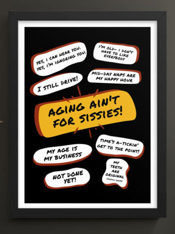 Mounted on a dark grey wall above a dark cabinet is a large black poster black wood framed print with a large  yellow bubble quote in the center that says, Aging Aint For Sissies. Several quotes surround it with funny old people quips.