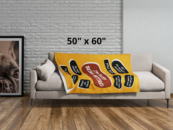 Lying across a grey couch is a large yellow throw blanket with a large red quote bubble in the center that says, I'm Busy Being Tired. Several black quote bubbles surround the center quote with several funny old people quips. Size 50 by 60 inches.