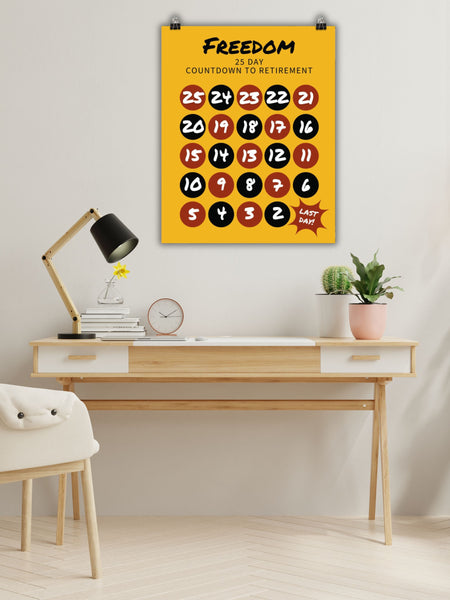 Clipped to a wall above a modern wood desk is a 25-day countdown to retirement and freedom sign and chart in yellow. Red and black circles with white numbers countdown from 25 to the last day.