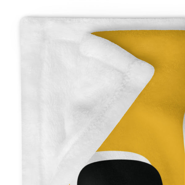 Close up detail of a folded corner of a yellow throw showing the soft, white fabric on the reverse side.